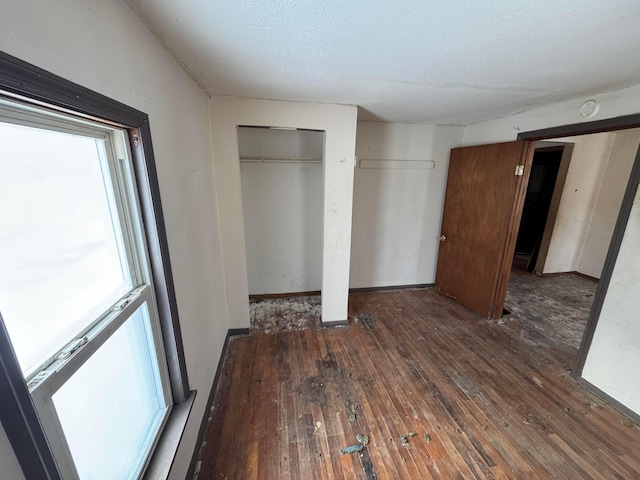 unfurnished bedroom with dark wood-type flooring and a textured ceiling