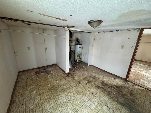 basement featuring water heater and a textured ceiling