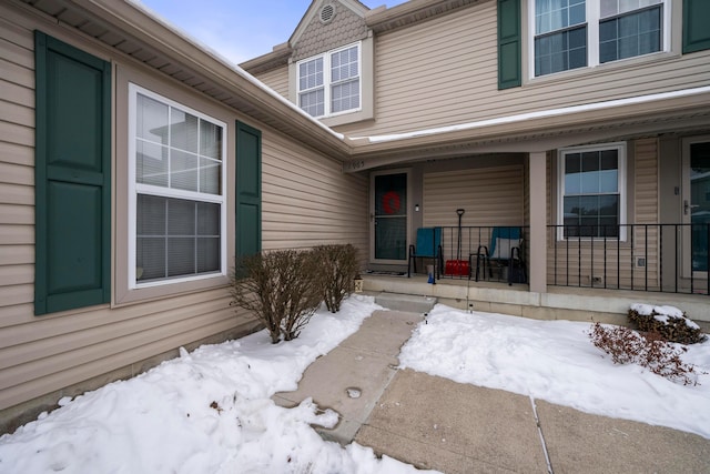 snow covered property entrance with covered porch