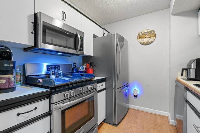 kitchen featuring baseboards, light wood-style floors, appliances with stainless steel finishes, a textured ceiling, and white cabinetry