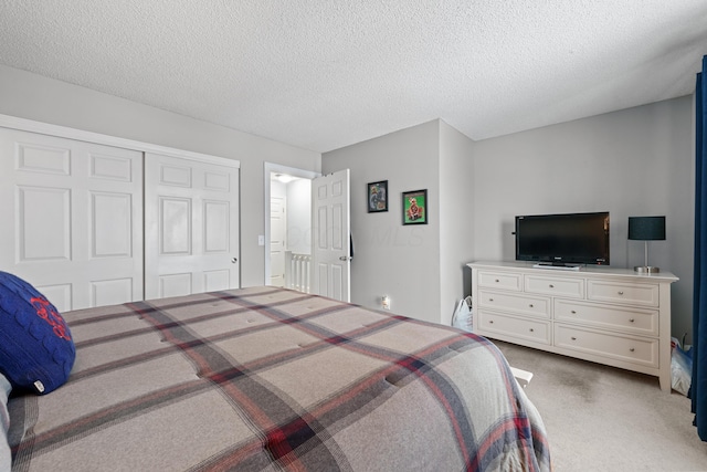 bedroom with a closet, light colored carpet, and a textured ceiling