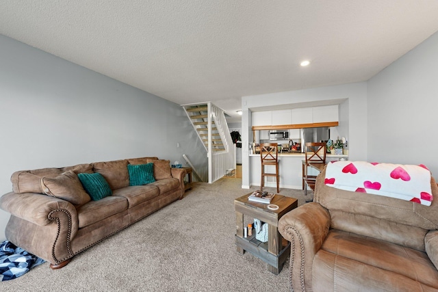 living room with stairway, carpet, and a textured ceiling