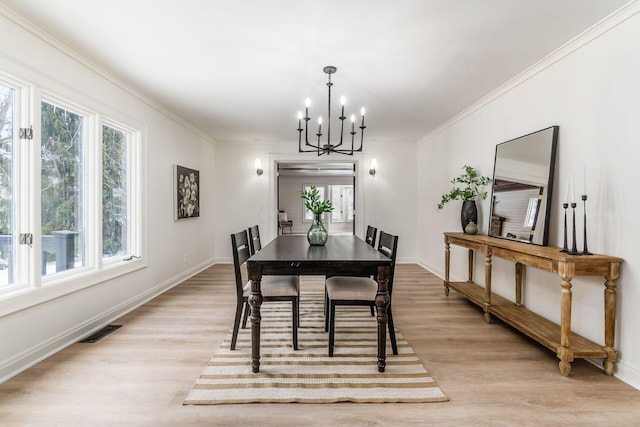 dining space featuring crown molding, light hardwood / wood-style flooring, and a notable chandelier