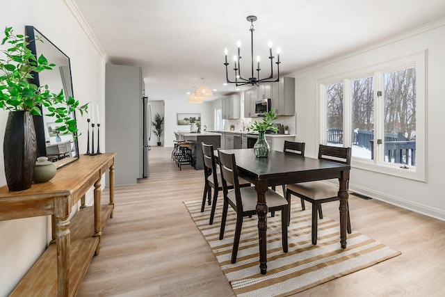 dining area featuring crown molding, a chandelier, and light wood-type flooring