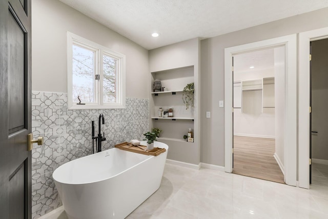 bathroom with a tub, a textured ceiling, and tile patterned floors