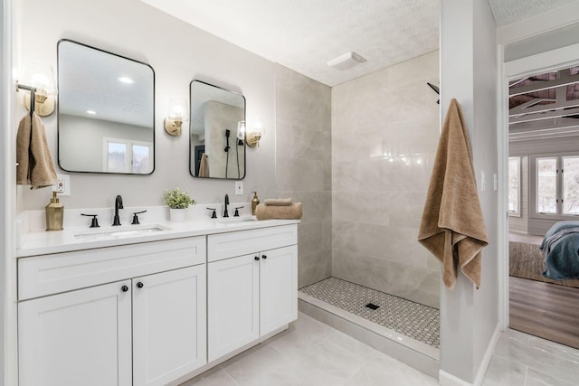 bathroom featuring a tile shower, a healthy amount of sunlight, vanity, and tile patterned flooring