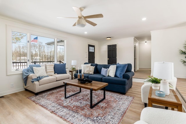 living room with light wood-type flooring, ceiling fan, and crown molding