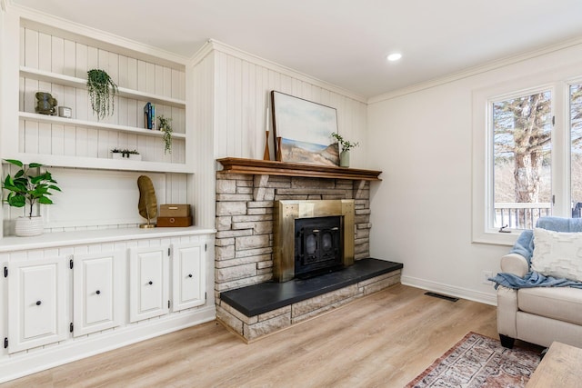 living room with crown molding, a wood stove, and light hardwood / wood-style flooring