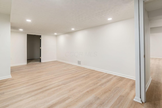 basement with a textured ceiling and light hardwood / wood-style floors