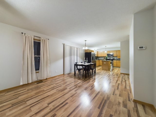 dining room with light wood-type flooring and a notable chandelier