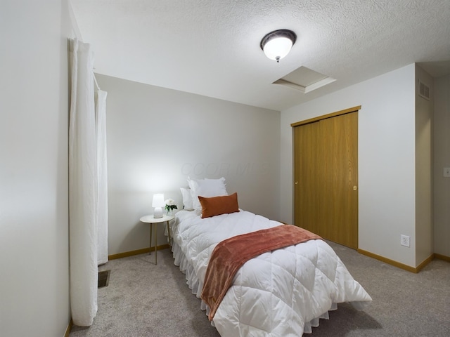 bedroom with a textured ceiling, a closet, and light colored carpet