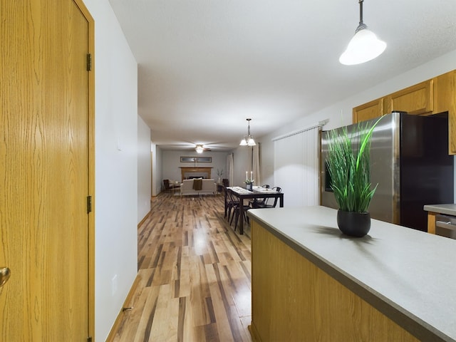 kitchen featuring light hardwood / wood-style flooring, stainless steel fridge, and pendant lighting