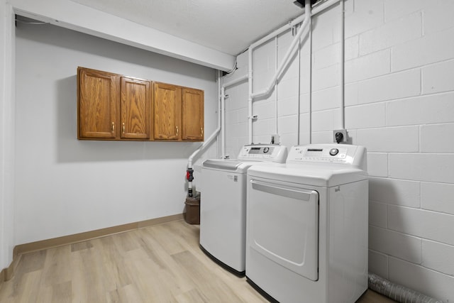 washroom with cabinets, independent washer and dryer, and light hardwood / wood-style flooring