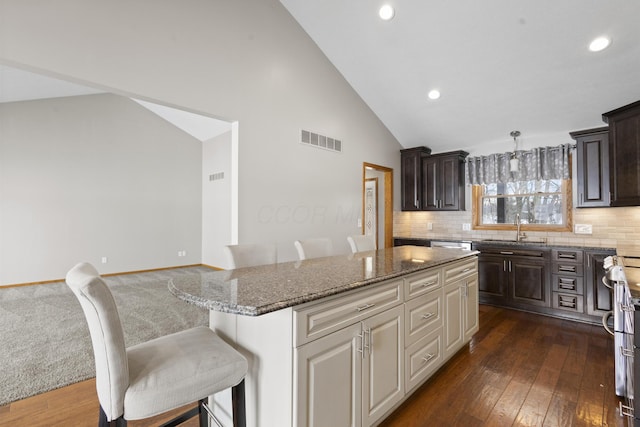 kitchen with a kitchen breakfast bar, dark hardwood / wood-style flooring, sink, and a kitchen island