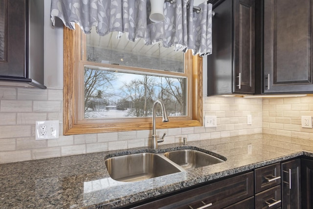 kitchen with sink, dark stone countertops, backsplash, and dark brown cabinetry