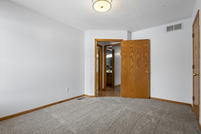 spare room with a textured ceiling and carpet flooring