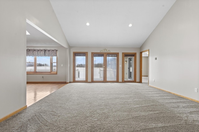 unfurnished living room with light carpet and high vaulted ceiling