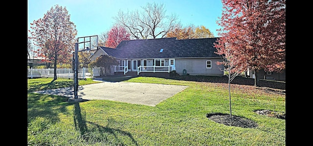 rear view of house featuring basketball court and a lawn