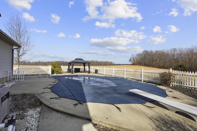 view of pool with a gazebo, a diving board, a patio area, and a rural view