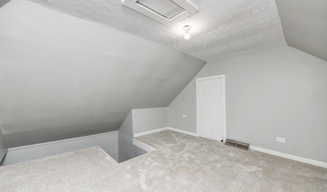 additional living space featuring lofted ceiling, carpet floors, and a textured ceiling