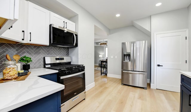 kitchen with backsplash, white cabinets, stainless steel appliances, light stone countertops, and light wood-type flooring