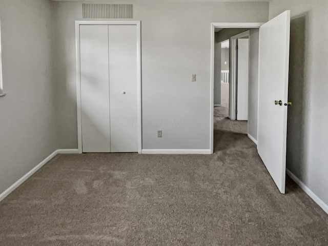 unfurnished bedroom with dark carpet and a closet