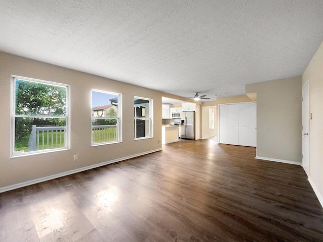 unfurnished living room featuring a textured ceiling, dark wood-type flooring, plenty of natural light, and ceiling fan