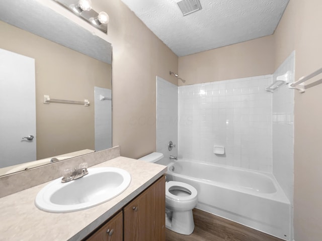 full bathroom with toilet, a textured ceiling, hardwood / wood-style floors, shower / washtub combination, and vanity