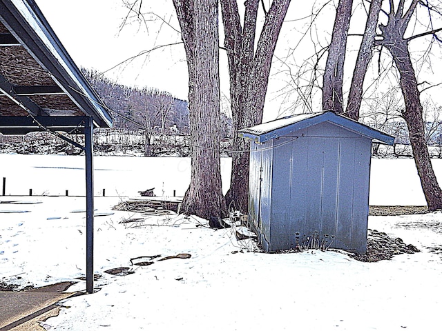 yard layered in snow featuring a storage shed