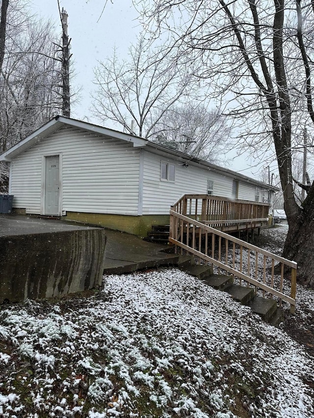 snow covered back of property with a deck