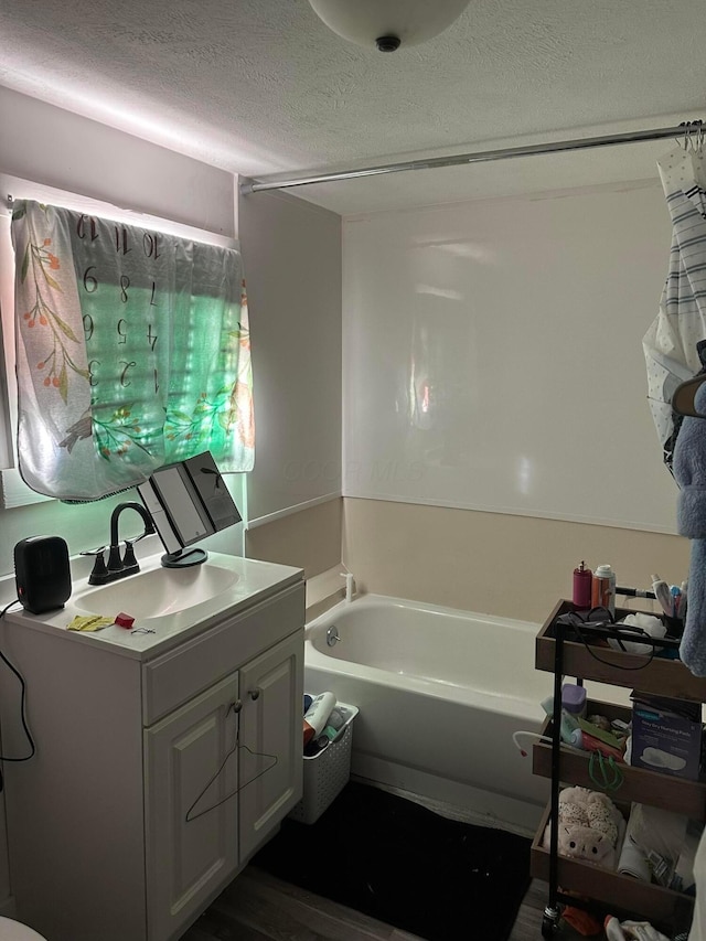 bathroom with vanity, a bathtub, and a textured ceiling