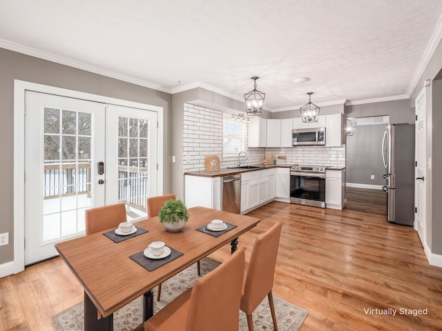 dining room with ornamental molding, french doors, baseboards, and light wood finished floors