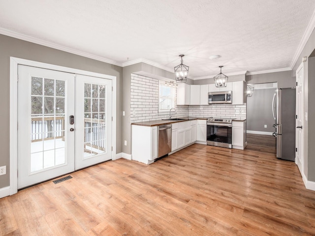 kitchen with visible vents, appliances with stainless steel finishes, ornamental molding, a sink, and light wood-type flooring