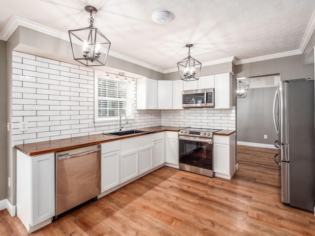 kitchen featuring a chandelier, stainless steel appliances, butcher block counters, and a sink