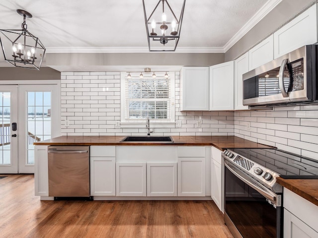 kitchen with a chandelier, stainless steel appliances, butcher block counters, and a sink