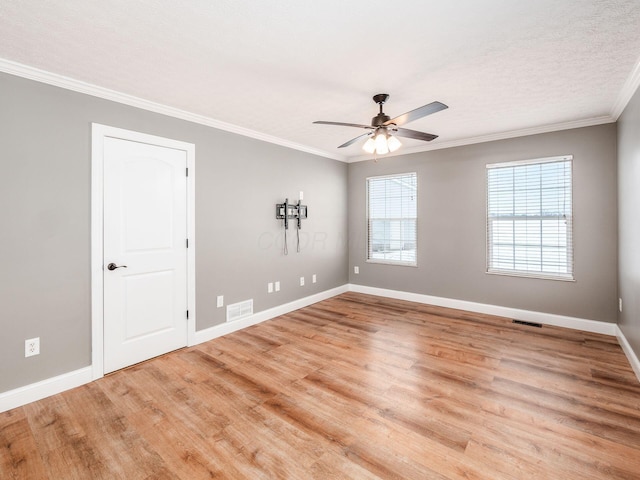 spare room with visible vents, crown molding, light wood-style flooring, and baseboards