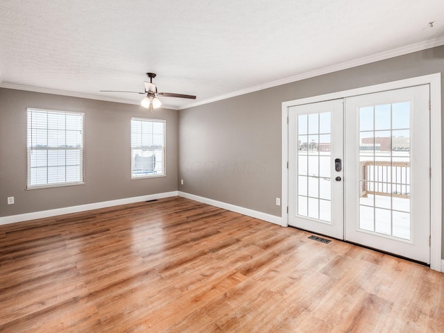 spare room with light wood-style flooring, visible vents, baseboards, french doors, and ornamental molding