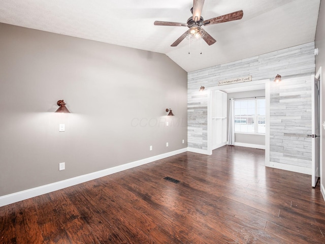 spare room with ceiling fan, vaulted ceiling, baseboards, and wood finished floors