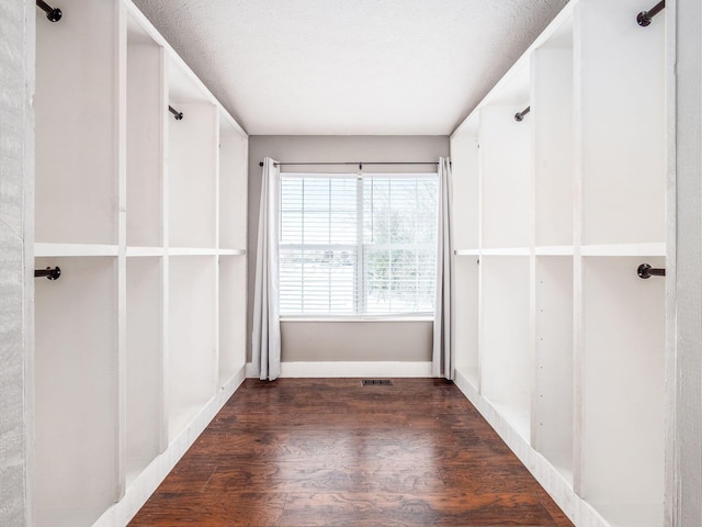 spare room with a textured ceiling, wood finished floors, visible vents, and baseboards