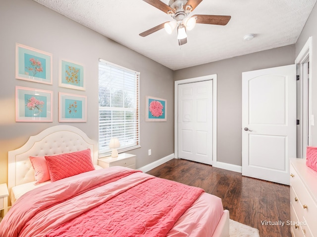 bedroom with a closet, dark wood-type flooring, ceiling fan, a textured ceiling, and baseboards