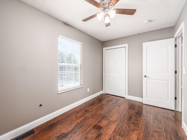 unfurnished bedroom with visible vents, baseboards, dark wood finished floors, a textured ceiling, and a closet