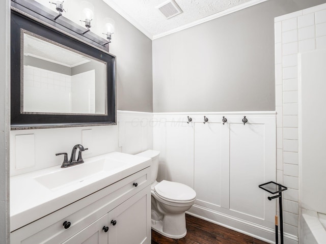 bathroom with visible vents, wainscoting, toilet, wood finished floors, and vanity