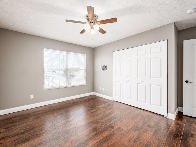 unfurnished bedroom featuring a textured ceiling, a closet, wood finished floors, and baseboards