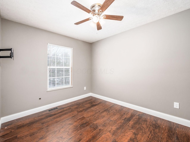 spare room featuring visible vents, dark wood finished floors, baseboards, and ceiling fan