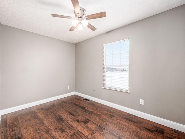 spare room with dark wood-style flooring, visible vents, a ceiling fan, a textured ceiling, and baseboards