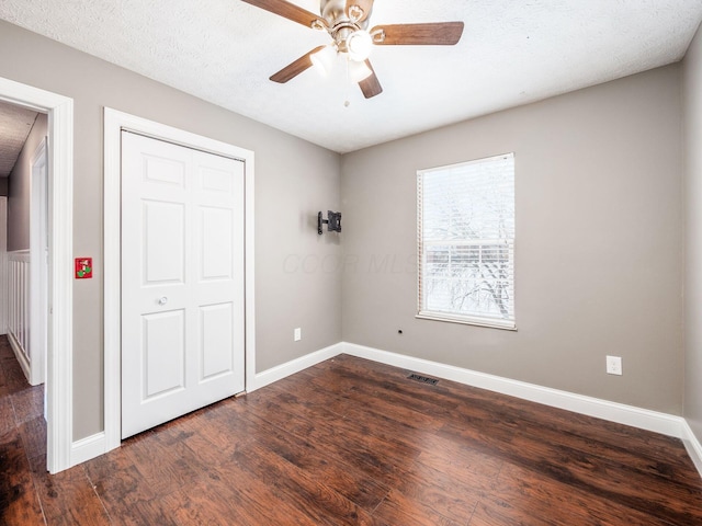 unfurnished bedroom with baseboards, a textured ceiling, visible vents, and wood finished floors