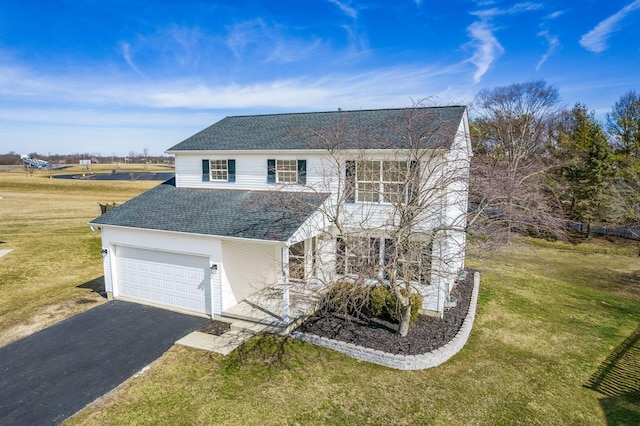 traditional-style home featuring a garage, driveway, a shingled roof, and a front lawn