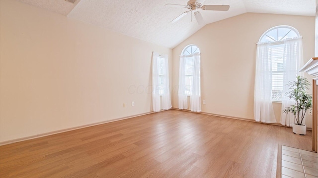 empty room with vaulted ceiling, a wealth of natural light, and light hardwood / wood-style floors