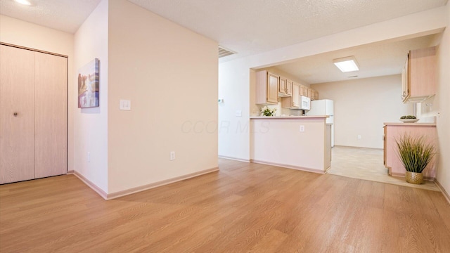 kitchen featuring light hardwood / wood-style floors, light brown cabinets, and a textured ceiling