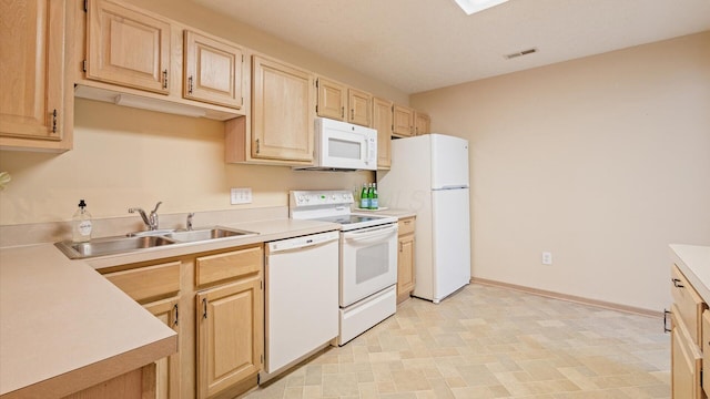 kitchen with light brown cabinetry, sink, and white appliances